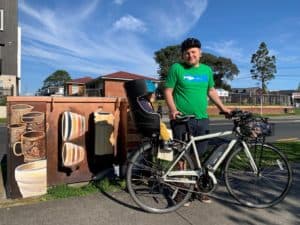 Dad and child on bike ride by painted power boxes in Auckland