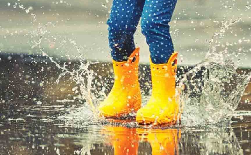Kid jumping in puddle in gumboots