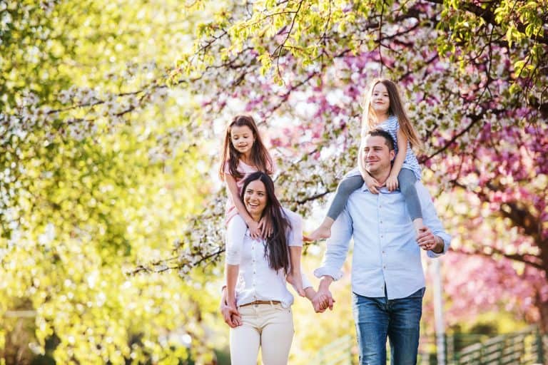 Family walking outdoors together under blossoming trees in spring.