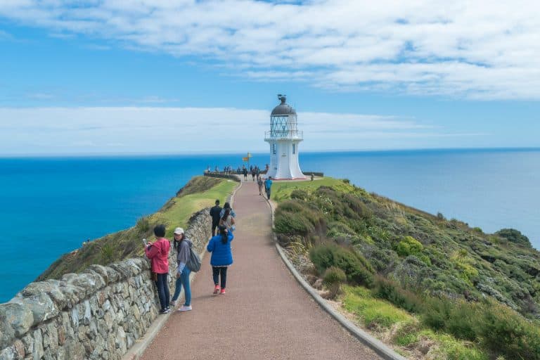 People walking around the lighthouse at Cape Reinga, at the top of the North Island of New Zealand