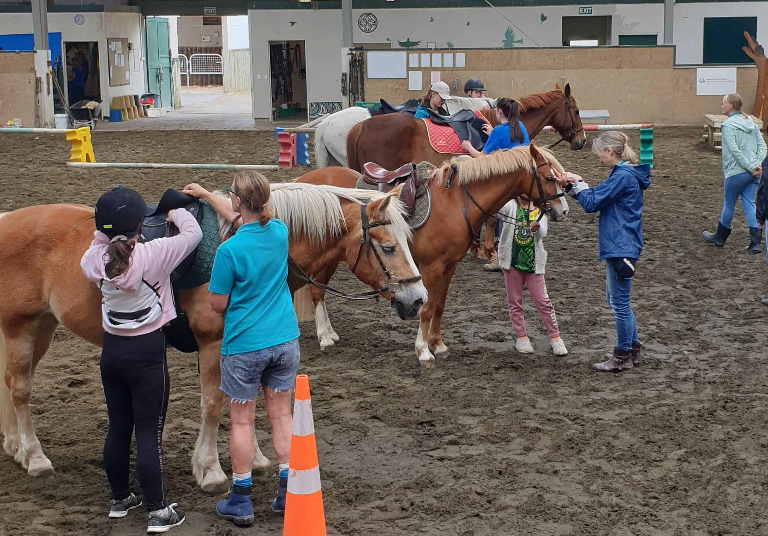 Children preparing ponies with instructors during the Ambury Park holiday riding programme