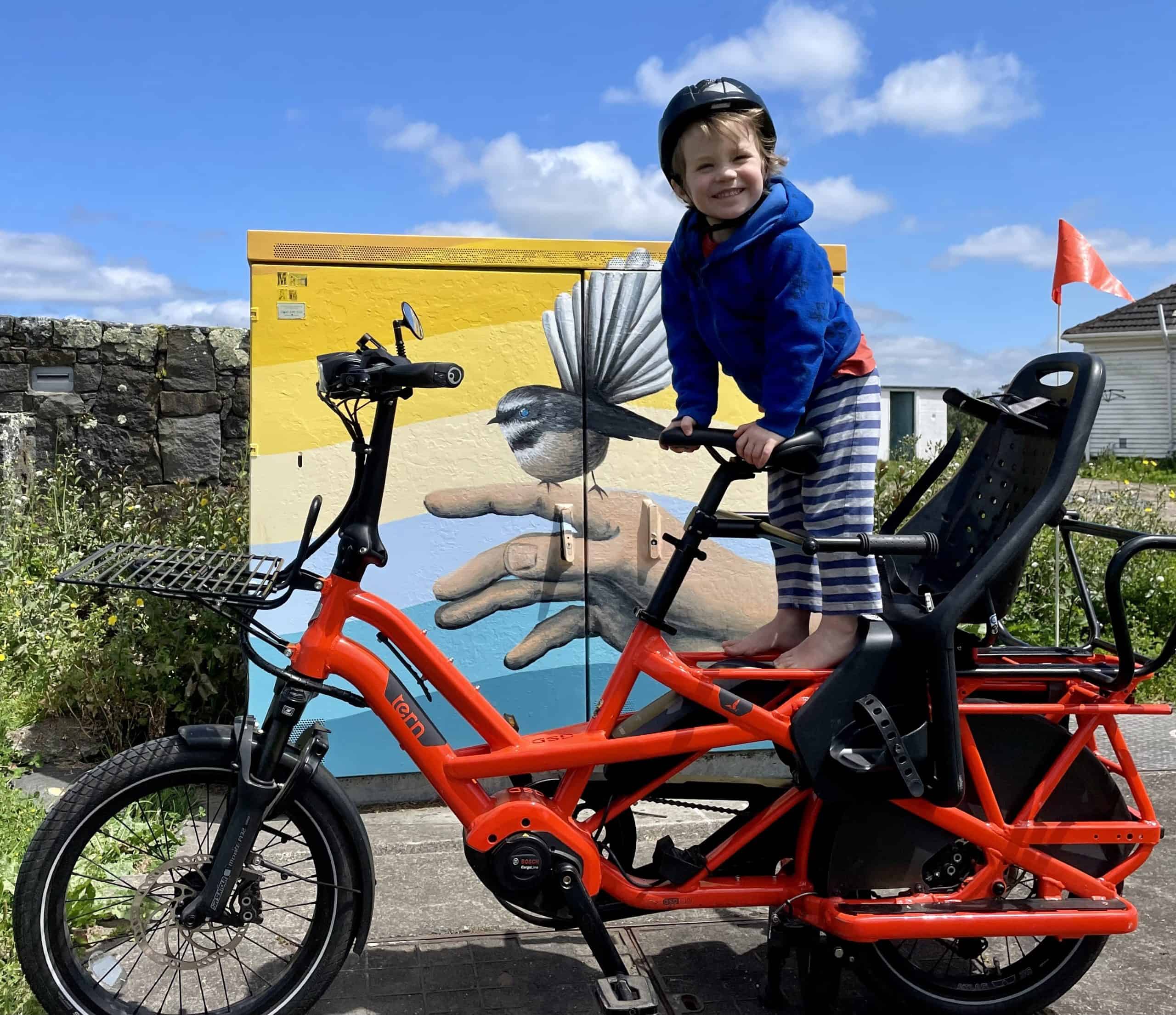 Child on an e-bike in front of mural in Rewa
