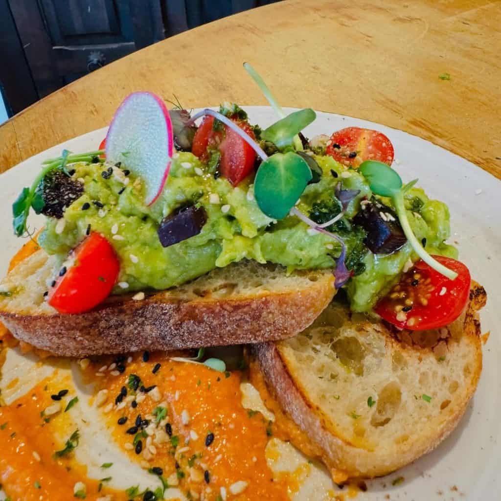 Colourful brunch plate with avocado toast, cherry tomatoes, radish and microgreens served on rustic bread at Eatery in Rothesay Bay
