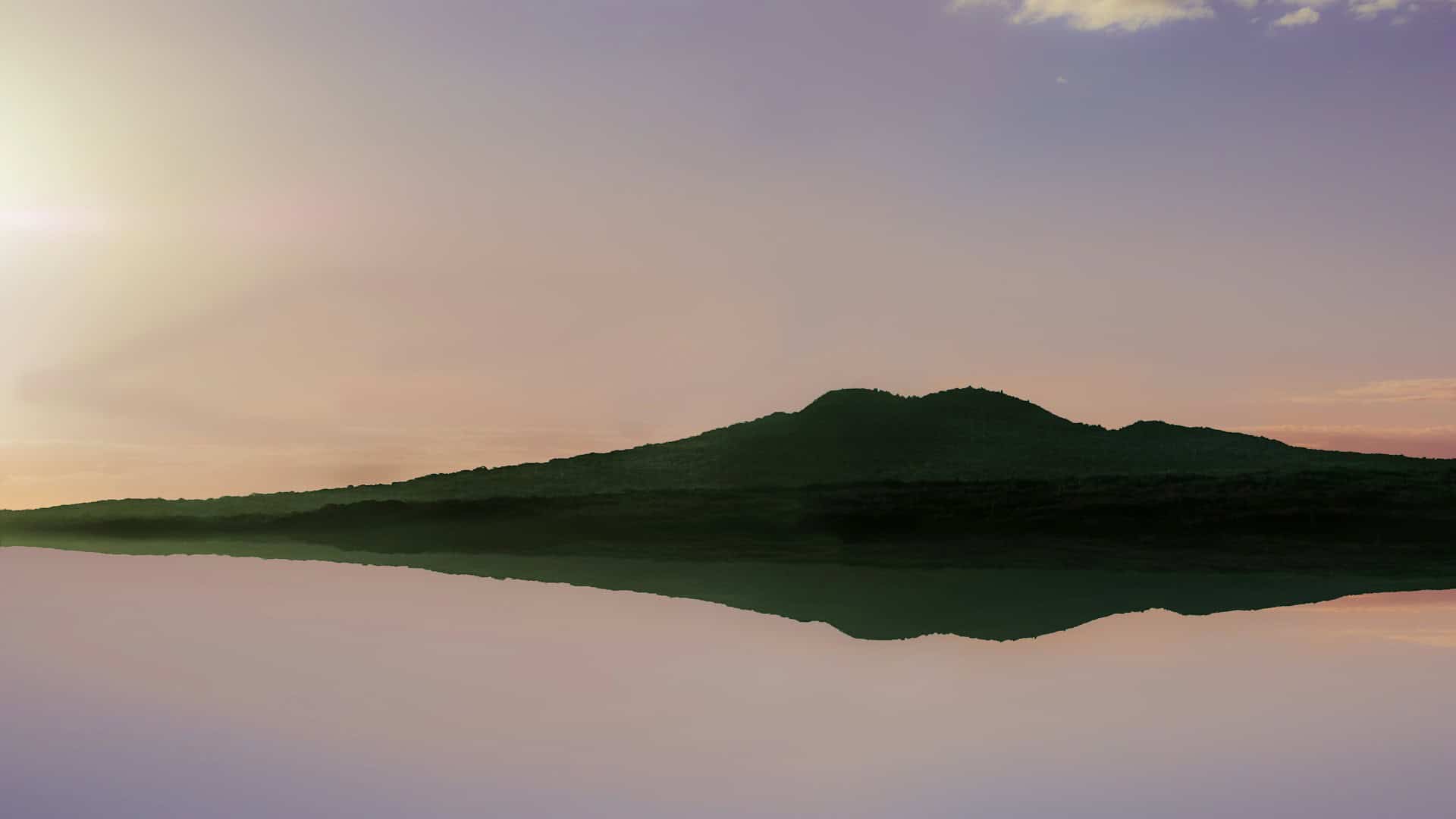 Rangitoto Island reflected in still water at sunset with a pink and purple sky
