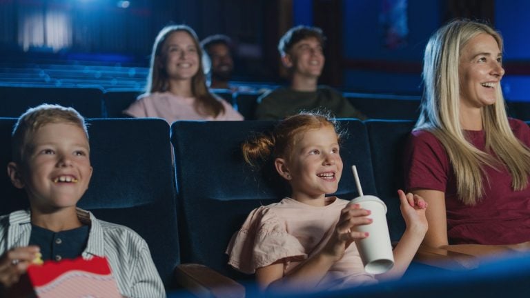 Young children watching a movie at the cinema with popcorn and drinks.