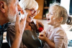 Grandparents laughing and spending time with their granddaughter in the kitchen.
