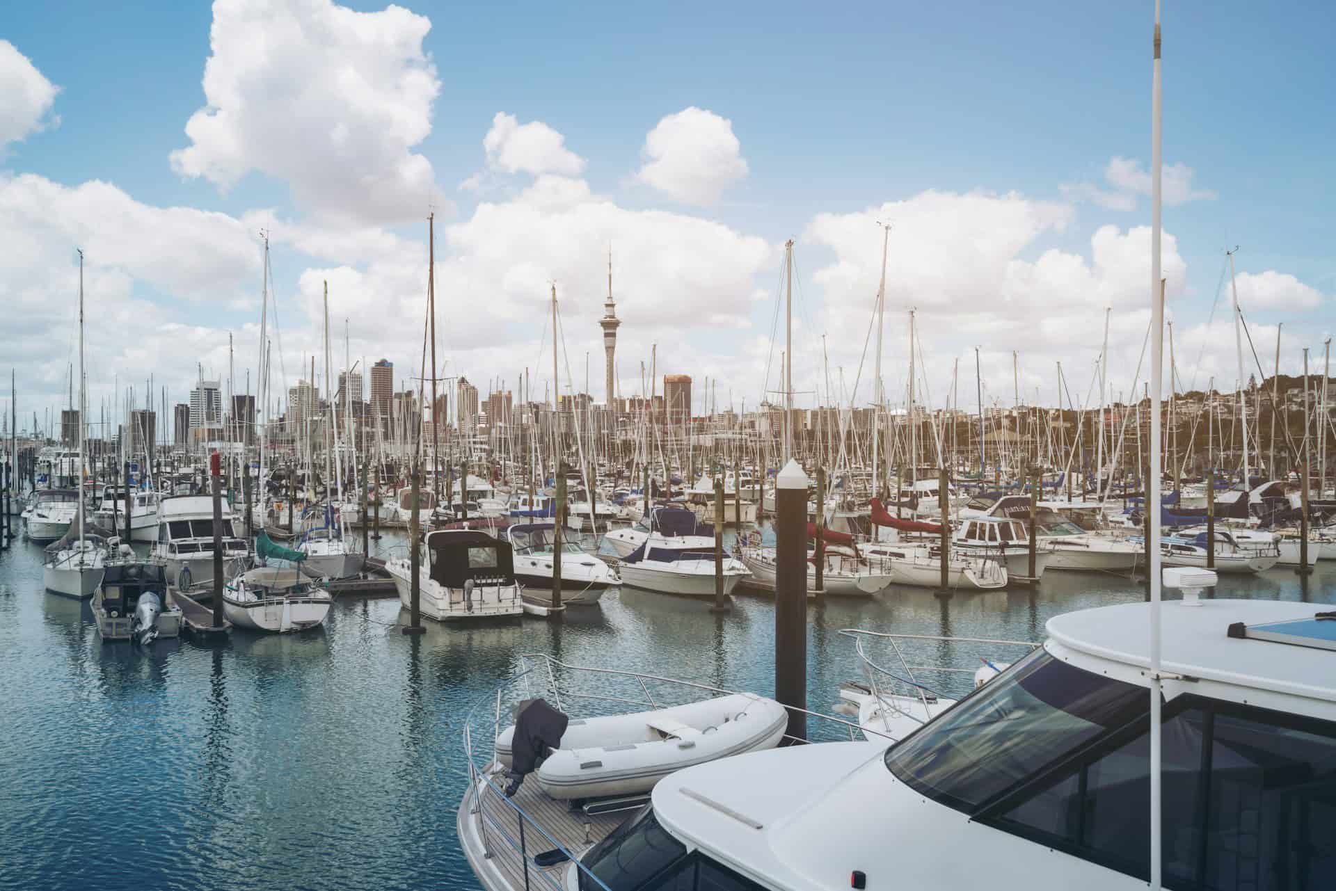Boats and yachts docked at Westhaven Marina with Auckland city skyline and Sky Tower in the background