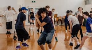 Teens participating in a contemporary youth theatre workshop on a polished wooden floor