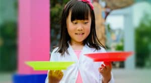 Young girl spinning colourful circus plates at Aotea Square play activity