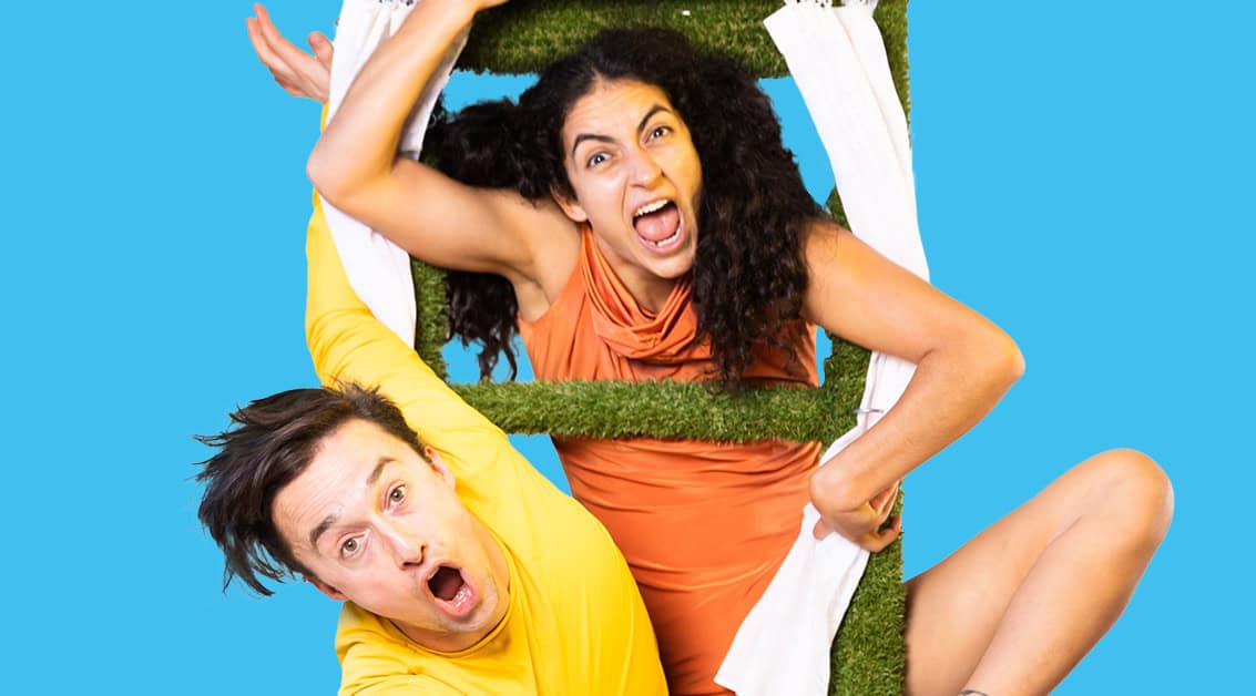 Two expressive performers burst through a green ladder frame in a colourful children’s theatre show