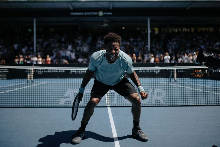 Tennis player celebrates with a roar on centre court at the ASB Classic in Auckland, surrounded by a cheering summer crowd