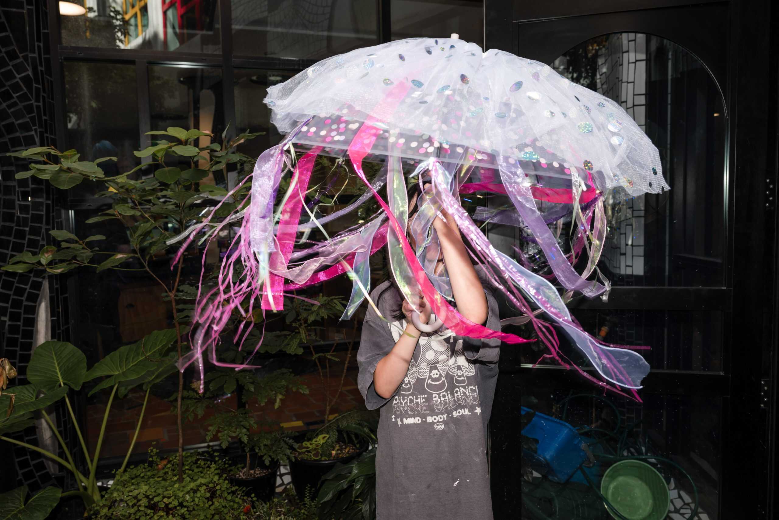 Child holding a bright jellyfish-style umbrella craft with ribbon streamers at The Sensory Lab