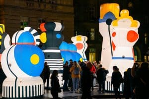 Families enjoying the giant illuminated chess installation Checkmate with 14 towering pieces
