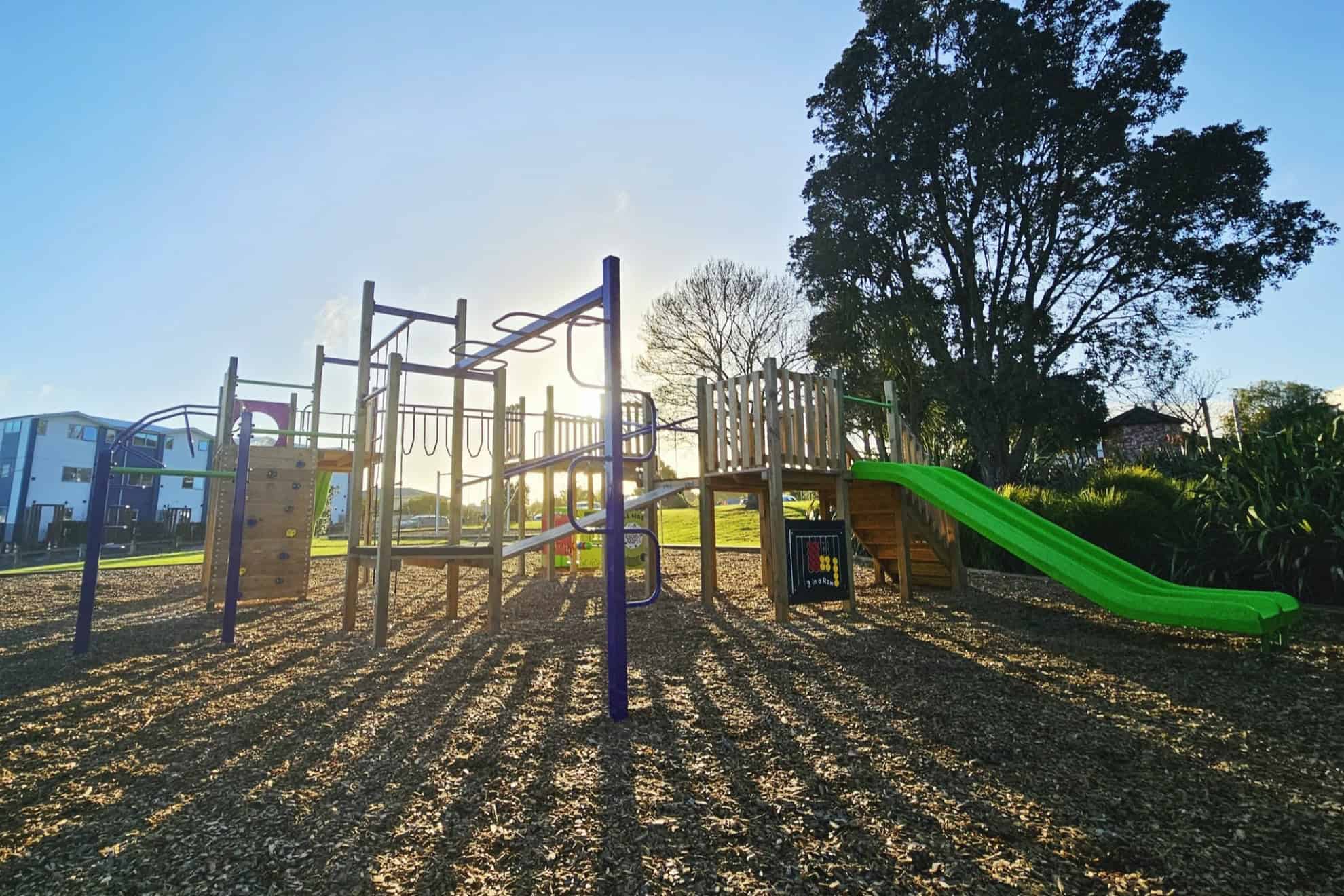 Wide view of Kaikoura Reserve Playground in Henderson with climbing frames and slide at sunset – photo by Playco Playgrounds